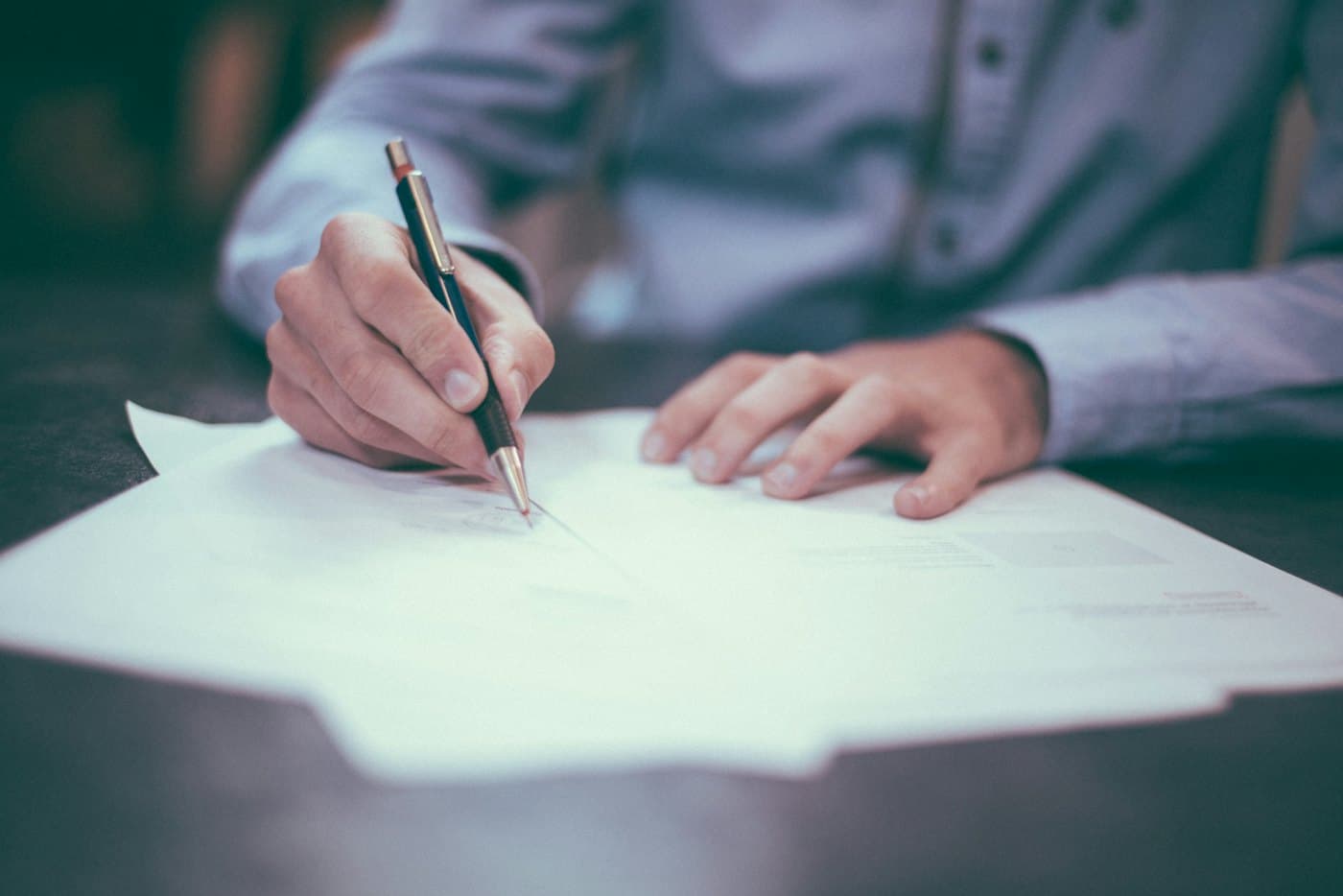 A person signing documents at a desk